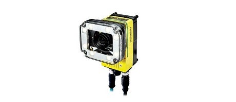 In-Sight D900 黄色と黒の保護ケースに収められた産業用カメラ。下部には2本のケーブルが接続されている。